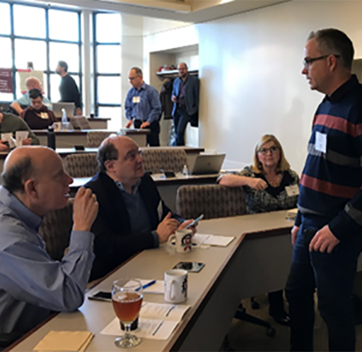 People sitting at a meeting room and talking to a person standing up